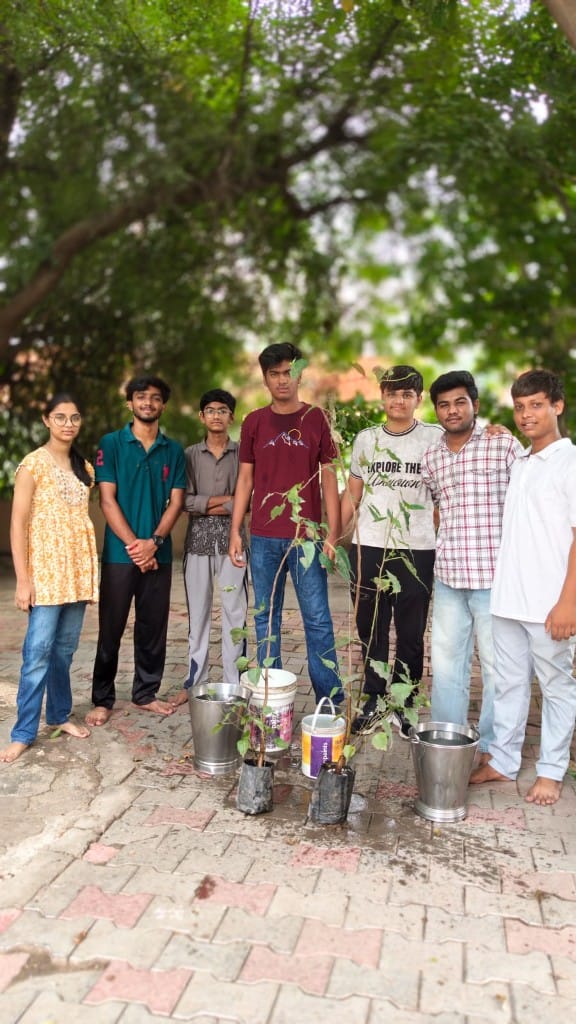 Volunteers with saplings and water buckets prepared for temple plantation seva